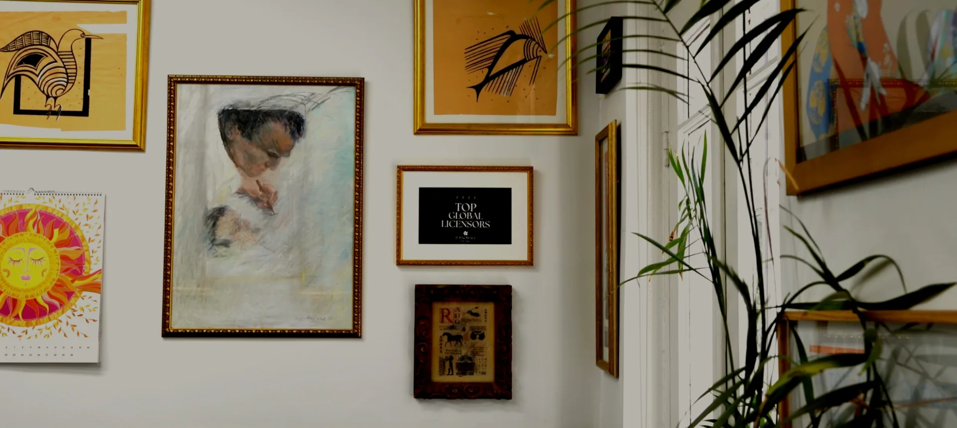 Gallery wall with framed art and industry awards in the studio